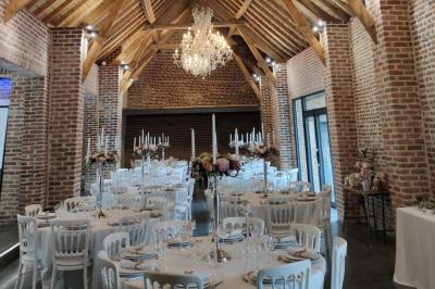 Photographie en noir et blanc d'un couple s'embrassant, la femme en robe de mariée, devant une structure en bois.