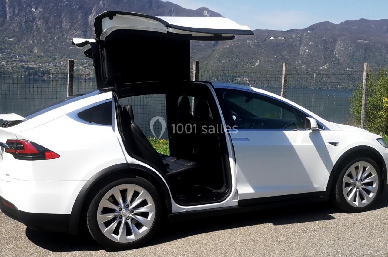 Photo David J. Location #9 Voiture blanche avec portes arrière ouvertes en ailes de mouette, stationnée près d'un lac et de montagnes.