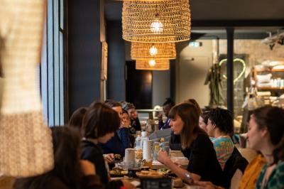 Table en bois dressée avec boissons, fleurs et collations, entourée d'étagères garnies de coussins colorés et décorations.