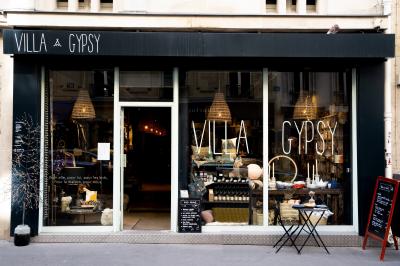 Table en bois dressée avec boissons, fleurs et collations, entourée d'étagères garnies de coussins colorés et décorations.