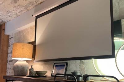 Table en bois dressée avec boissons, fleurs et collations, entourée d'étagères garnies de coussins colorés et décorations.