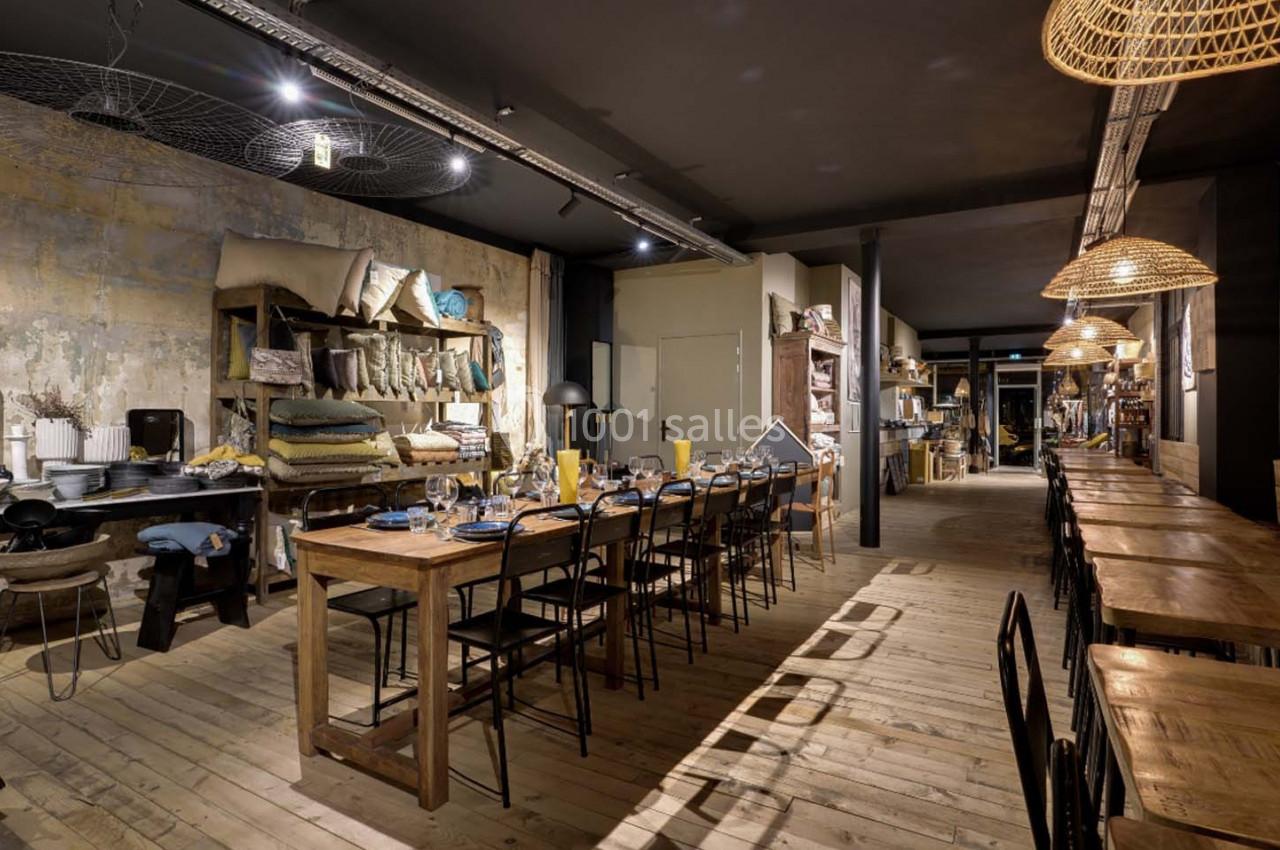 Salle de restaurant chaleureuse avec tables en bois, chaises noires, éclairage tamisé et décoration rustique.