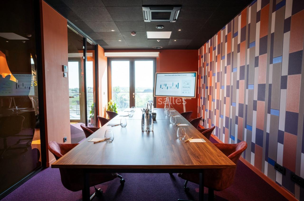 Salle de réunion moderne avec table en bois, chaises en cuir, écran affichant un graphique et grande fenêtre lumineuse.