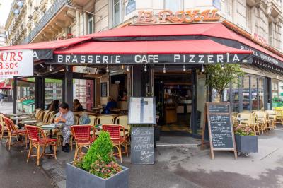 Façade d'une brasserie avec terrasse, tables occupées, menus affichés et enseigne ’Le Royal’ visible.