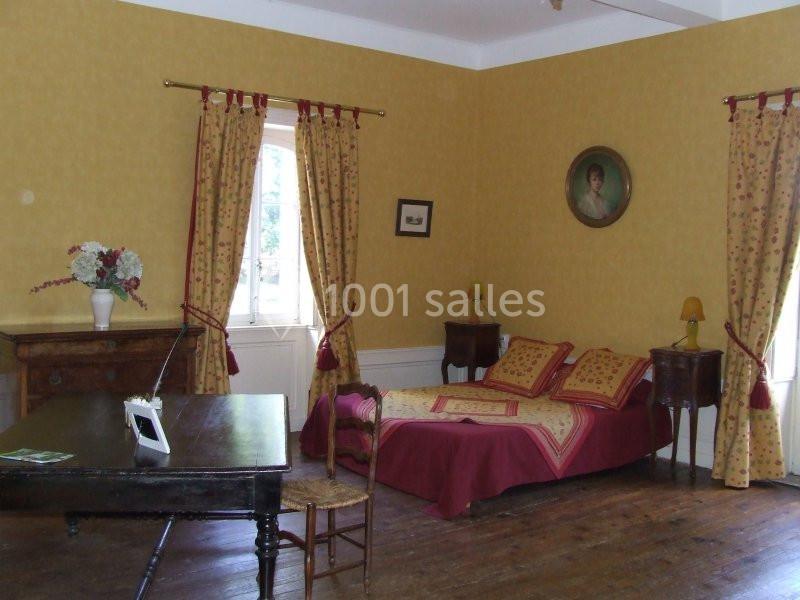 Chambre avec murs jaunes, lit double, rideaux assortis, meubles en bois et décoration murale.