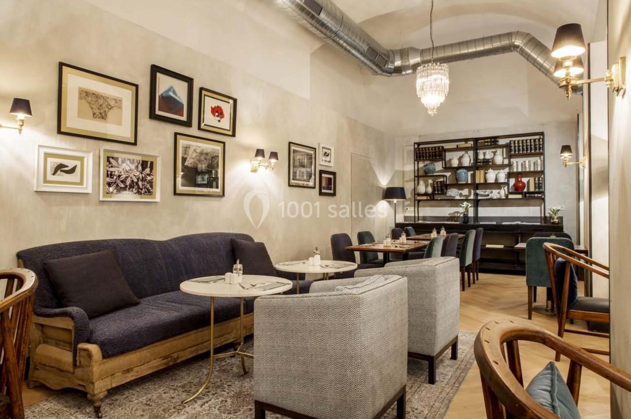 Salon cosy avec canapés, fauteuils, tables basses, décorations murales et étagères visibles dans un cadre élégant.