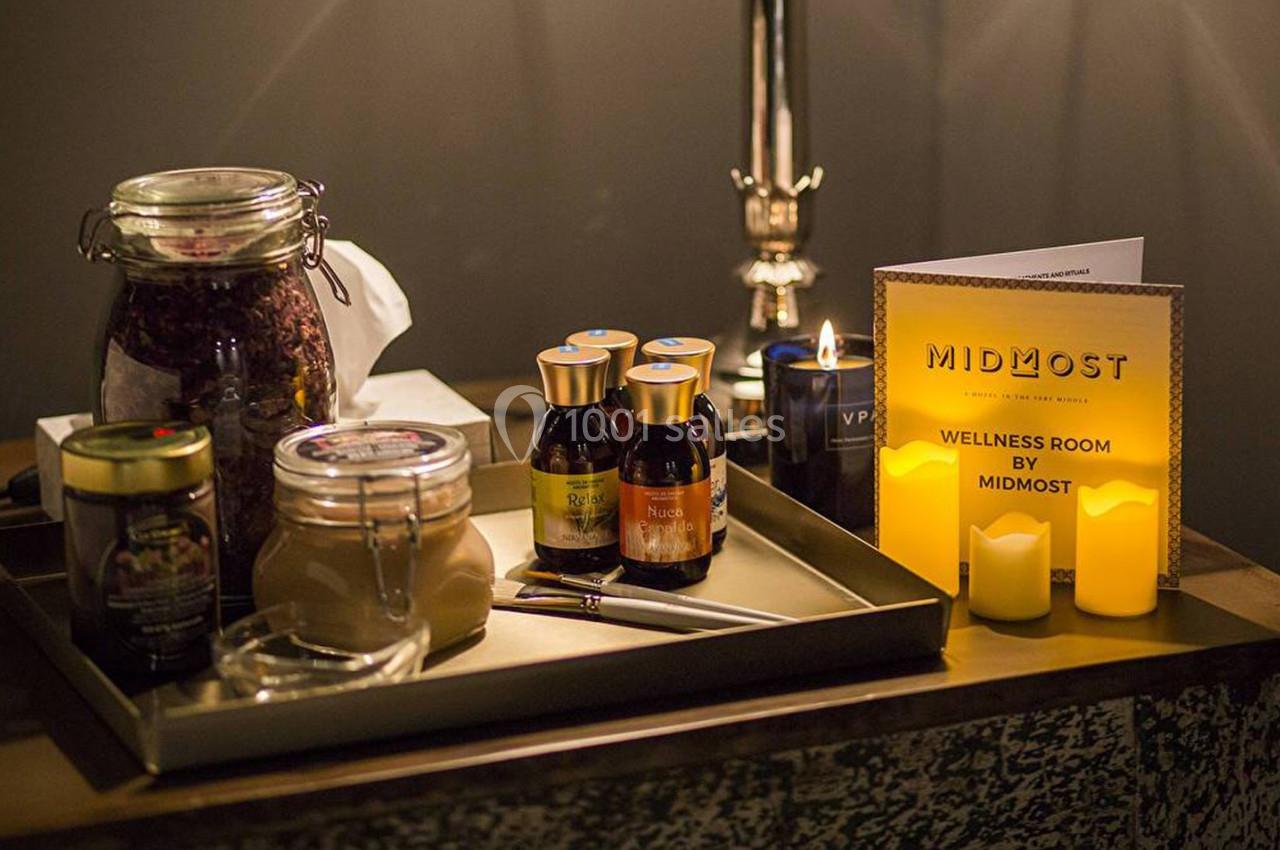 Plateau contenant des pots en verre, des bouteilles, une bougie et un dépliant dans un environnement tamisé.