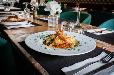 Cour intérieure éclairée de nuit, avec des chaises et tables sous un arbre aux feuilles jaunies en automne.