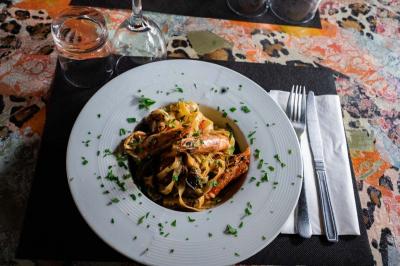 Cour intérieure éclairée de nuit, avec des chaises et tables sous un arbre aux feuilles jaunies en automne.