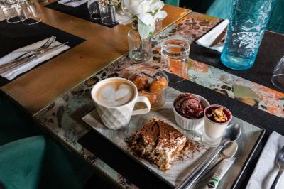 Cour intérieure éclairée de nuit, avec des chaises et tables sous un arbre aux feuilles jaunies en automne.