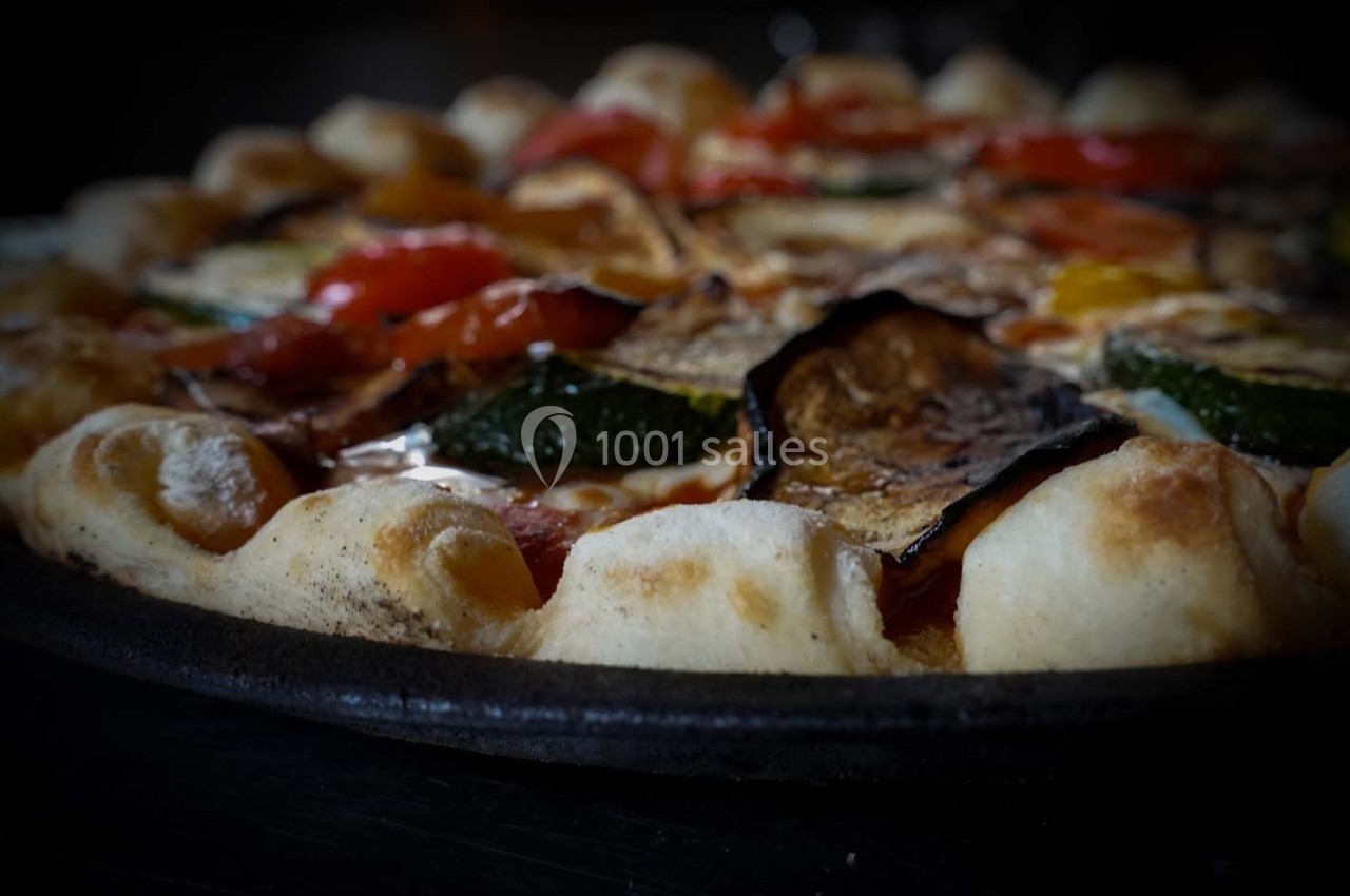 Pizza garnie de légumes grillés, notamment courgettes, aubergines et poivrons, sur une pâte dorée et moelleuse.