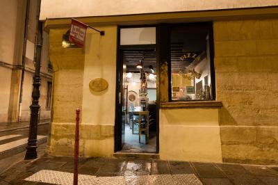 Cour intérieure éclairée de nuit, avec des chaises et tables sous un arbre aux feuilles jaunies en automne.