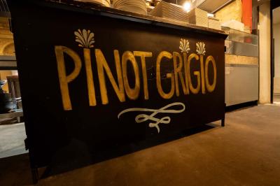 Cour intérieure éclairée de nuit, avec des chaises et tables sous un arbre aux feuilles jaunies en automne.