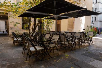 Cour intérieure éclairée de nuit, avec des chaises et tables sous un arbre aux feuilles jaunies en automne.