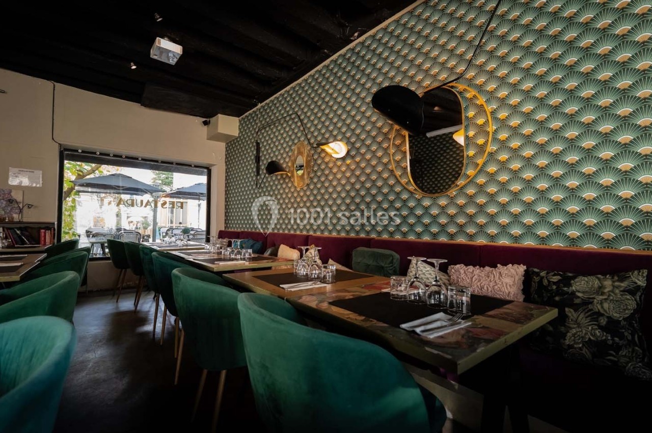 Salle de restaurant élégante avec tables dressées, chaises vertes et mur décoratif texturé avec miroirs et éclairage.