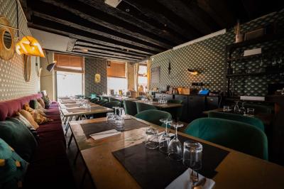 Cour intérieure éclairée de nuit, avec des chaises et tables sous un arbre aux feuilles jaunies en automne.