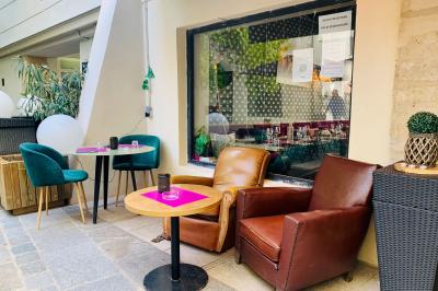 Cour intérieure éclairée de nuit, avec des chaises et tables sous un arbre aux feuilles jaunies en automne.