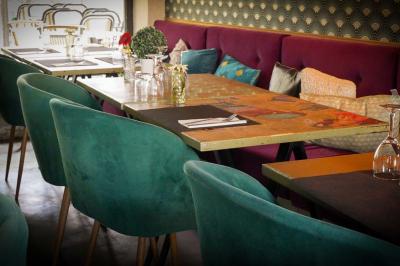 Cour intérieure éclairée de nuit, avec des chaises et tables sous un arbre aux feuilles jaunies en automne.