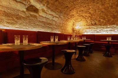 Cour intérieure éclairée de nuit, avec des chaises et tables sous un arbre aux feuilles jaunies en automne.