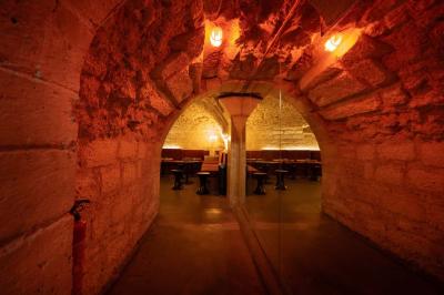 Cour intérieure éclairée de nuit, avec des chaises et tables sous un arbre aux feuilles jaunies en automne.
