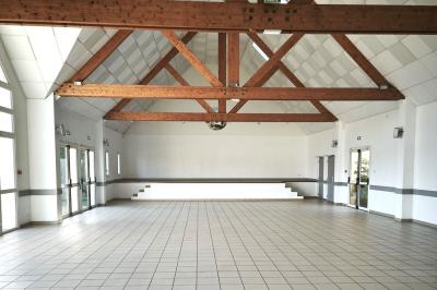 Cuisine professionnelle vide avec plans de travail en inox, murs carrelés blancs, fenêtres et extincteur visible.