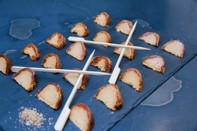 Tranches de viande séchée disposées sur une ardoise avec des noix et des piques en bois.