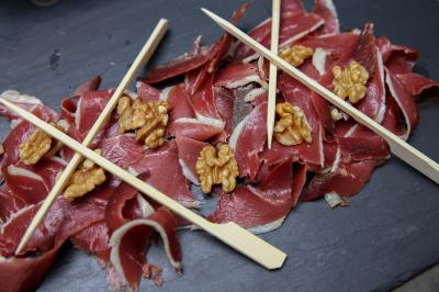 Tranches de viande séchée disposées sur une ardoise avec des noix et des piques en bois.
