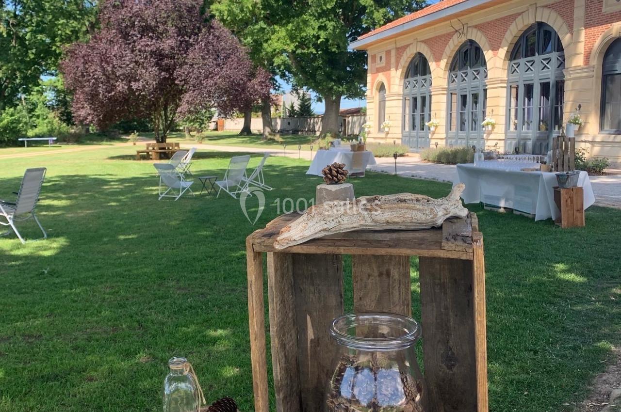 Table décorative en bois avec des éléments naturels, dans un jardin verdoyant près d'un bâtiment en briques.