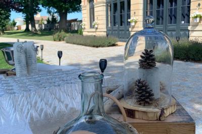 Table ronde élégamment dressée avec des assiettes blanches, des couverts dorés et un bouquet de roses, près d'une baie…