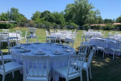 Table ronde élégamment dressée avec des assiettes blanches, des couverts dorés et un bouquet de roses, près d'une baie…