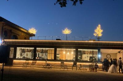 Table ronde élégamment dressée avec des assiettes blanches, des couverts dorés et un bouquet de roses, près d'une baie…