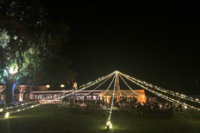 Table ronde élégamment dressée avec des assiettes blanches, des couverts dorés et un bouquet de roses, près d'une baie…