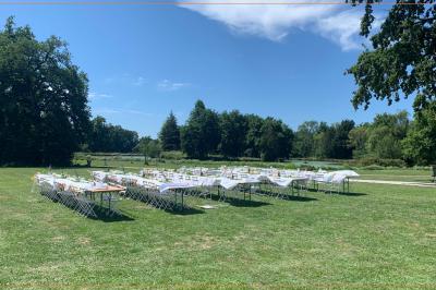 Table ronde élégamment dressée avec des assiettes blanches, des couverts dorés et un bouquet de roses, près d'une baie…