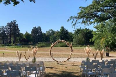 Table ronde élégamment dressée avec des assiettes blanches, des couverts dorés et un bouquet de roses, près d'une baie…