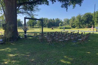Table ronde élégamment dressée avec des assiettes blanches, des couverts dorés et un bouquet de roses, près d'une baie…