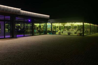 Table ronde élégamment dressée avec des assiettes blanches, des couverts dorés et un bouquet de roses, près d'une baie…