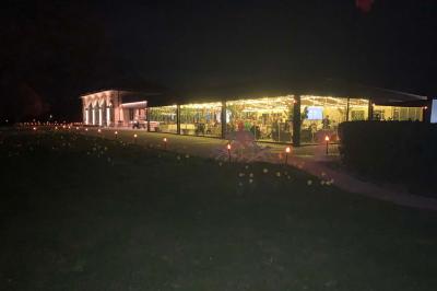 Table ronde élégamment dressée avec des assiettes blanches, des couverts dorés et un bouquet de roses, près d'une baie…