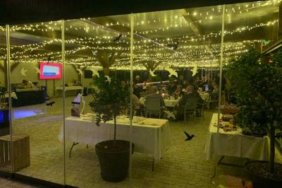 Table ronde élégamment dressée avec des assiettes blanches, des couverts dorés et un bouquet de roses, près d'une baie…