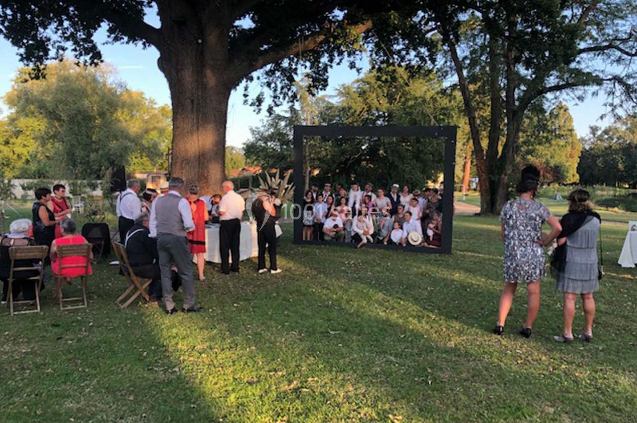 Un groupe de personnes rassemblées dans un parc, certaines posant dans un grand cadre noir sous un arbre.