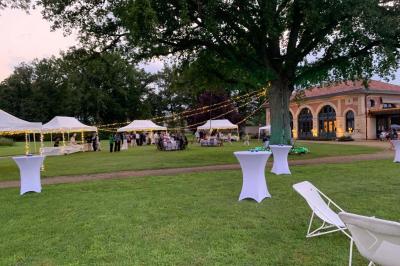 Table ronde élégamment dressée avec des assiettes blanches, des couverts dorés et un bouquet de roses, près d'une baie…