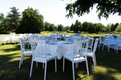 Table ronde élégamment dressée avec des assiettes blanches, des couverts dorés et un bouquet de roses, près d'une baie…