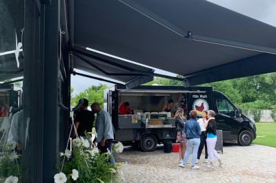 Table ronde élégamment dressée avec des assiettes blanches, des couverts dorés et un bouquet de roses, près d'une baie…