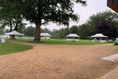Table ronde élégamment dressée avec des assiettes blanches, des couverts dorés et un bouquet de roses, près d'une baie…