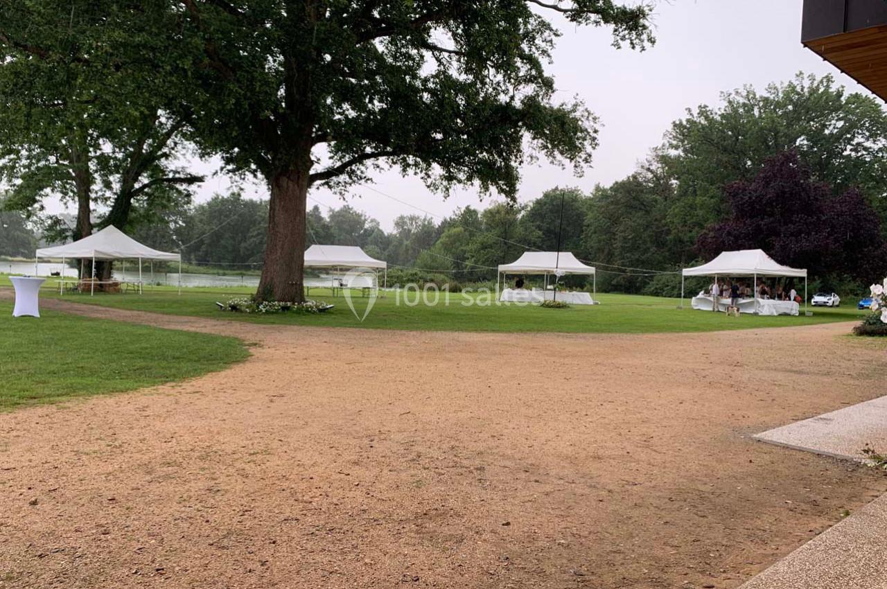 Tentes blanches installées sur une pelouse verdoyante entourée d'arbres, par temps couvert.