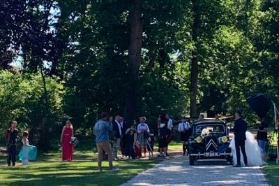 Table ronde élégamment dressée avec des assiettes blanches, des couverts dorés et un bouquet de roses, près d'une baie…