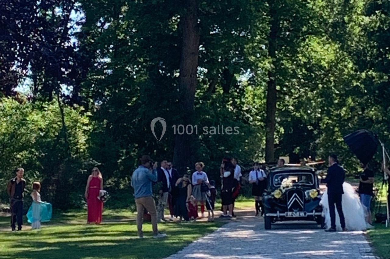 Un groupe de personnes rassemblé près d'une voiture ancienne décorée, dans un parc verdoyant.