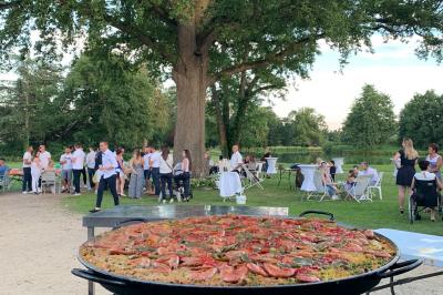 Table ronde élégamment dressée avec des assiettes blanches, des couverts dorés et un bouquet de roses, près d'une baie…