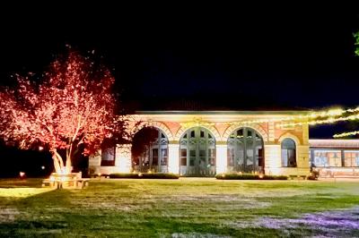Table ronde élégamment dressée avec des assiettes blanches, des couverts dorés et un bouquet de roses, près d'une baie…