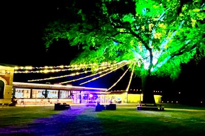 Table ronde élégamment dressée avec des assiettes blanches, des couverts dorés et un bouquet de roses, près d'une baie…