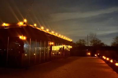 Table ronde élégamment dressée avec des assiettes blanches, des couverts dorés et un bouquet de roses, près d'une baie…